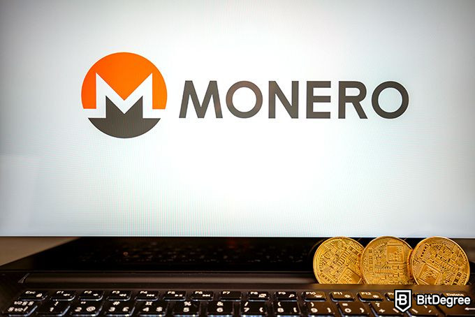 Mineria Monero: monedes Monero apilades davant de la pantalla d’un ordinador.